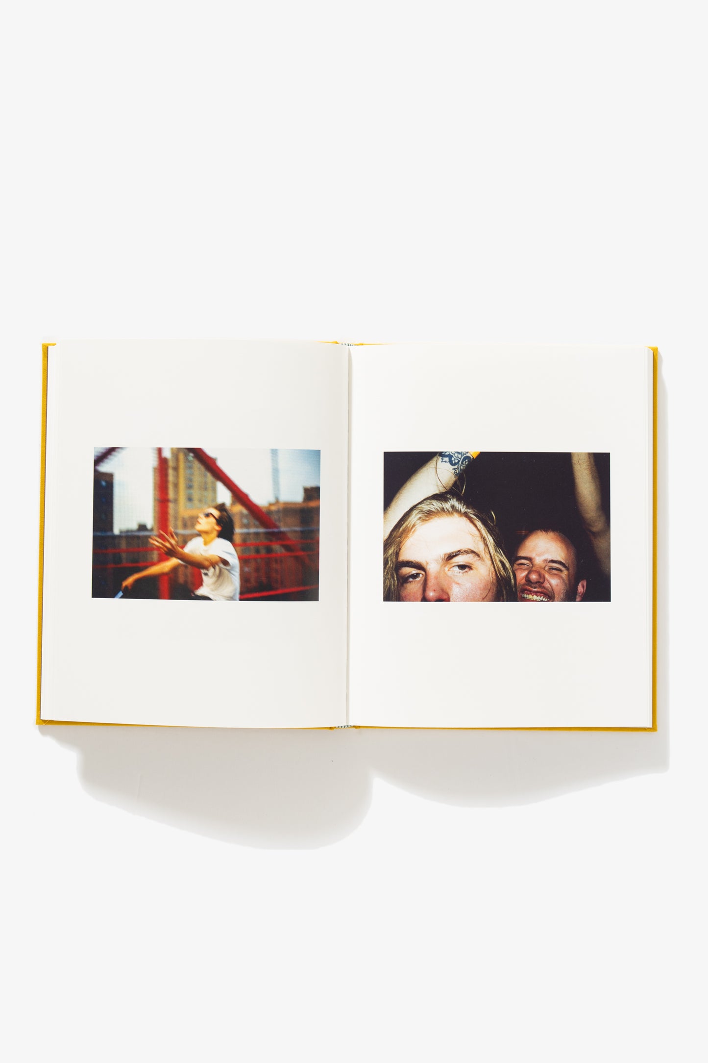 Spread of Everybody’s Guilty, No One’s To Blame. Verso shows a man riding his bike across a bridge, his face to the sky, and his left arm raised partially. Recto shows a close-up of two faces. The front face is partially obscured, the face behind him smiles gleefully.