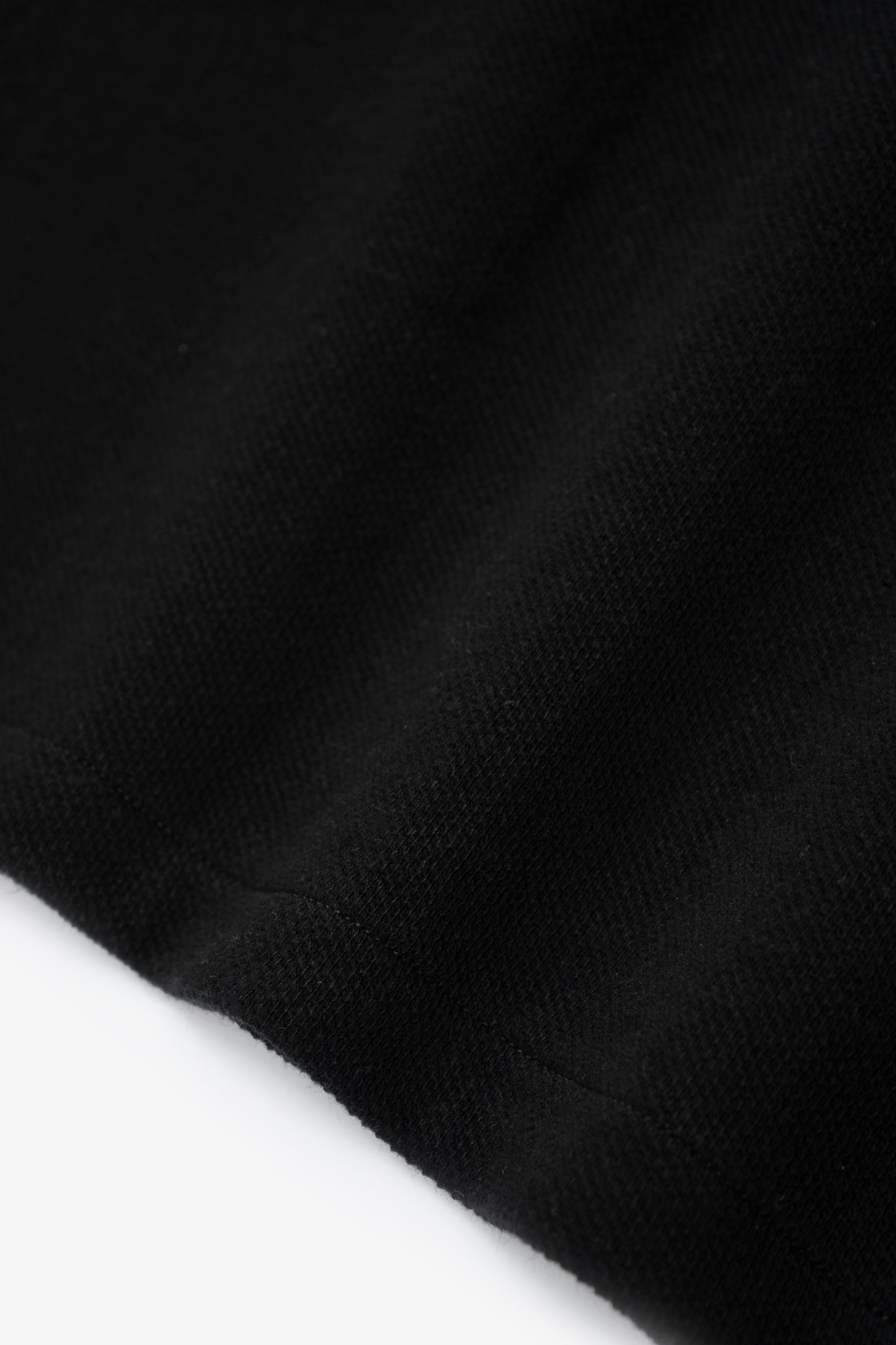 Hem detail of LW415CL Double Knit Polo in Black on a model