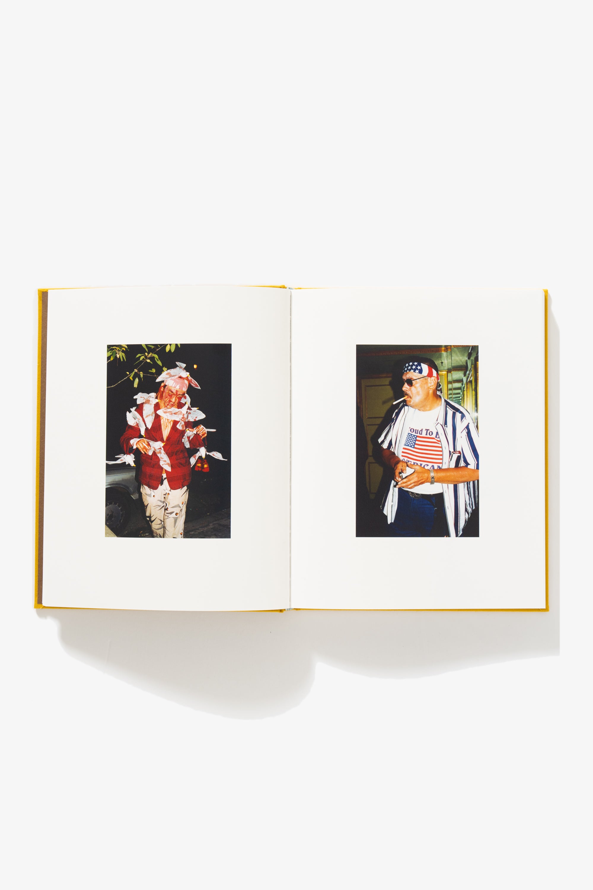 Spread of Everybody’s Guilty, No One’s To Blame. Verso shows a man covered in paper birds, stained red with an indeterminate substance. Recto shows a man wearing USA-themed clothing, an unlit cigarette in his mouth. His shirt reads “Proud To Be AMERICAN.” 