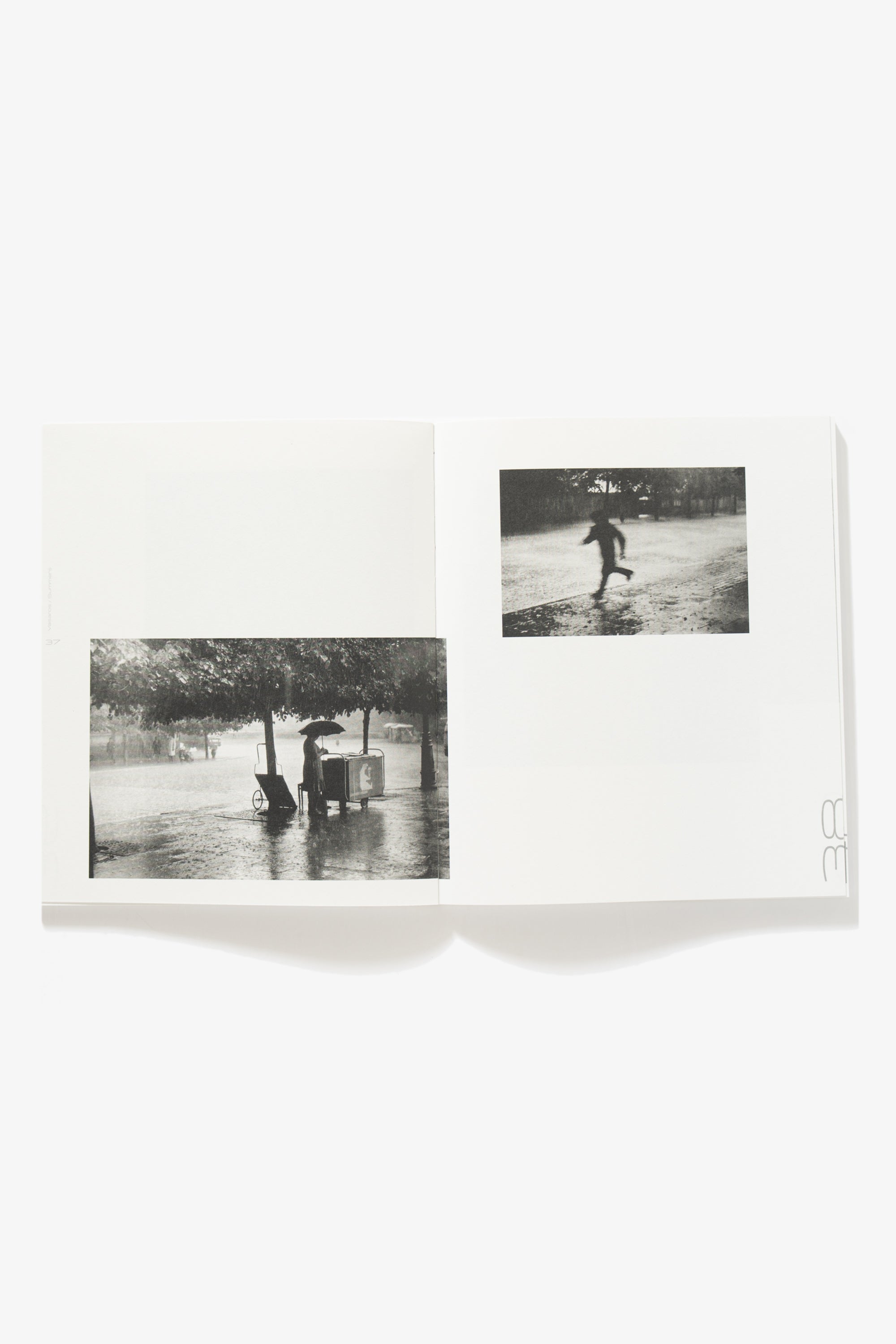 Spread of 85 Vasaros. Verso shows an image of a woman standing besides a cart underneath a tree holding an umbrella, protecting herself from the rain. Recto shows an indeterminate figure running through the rain.