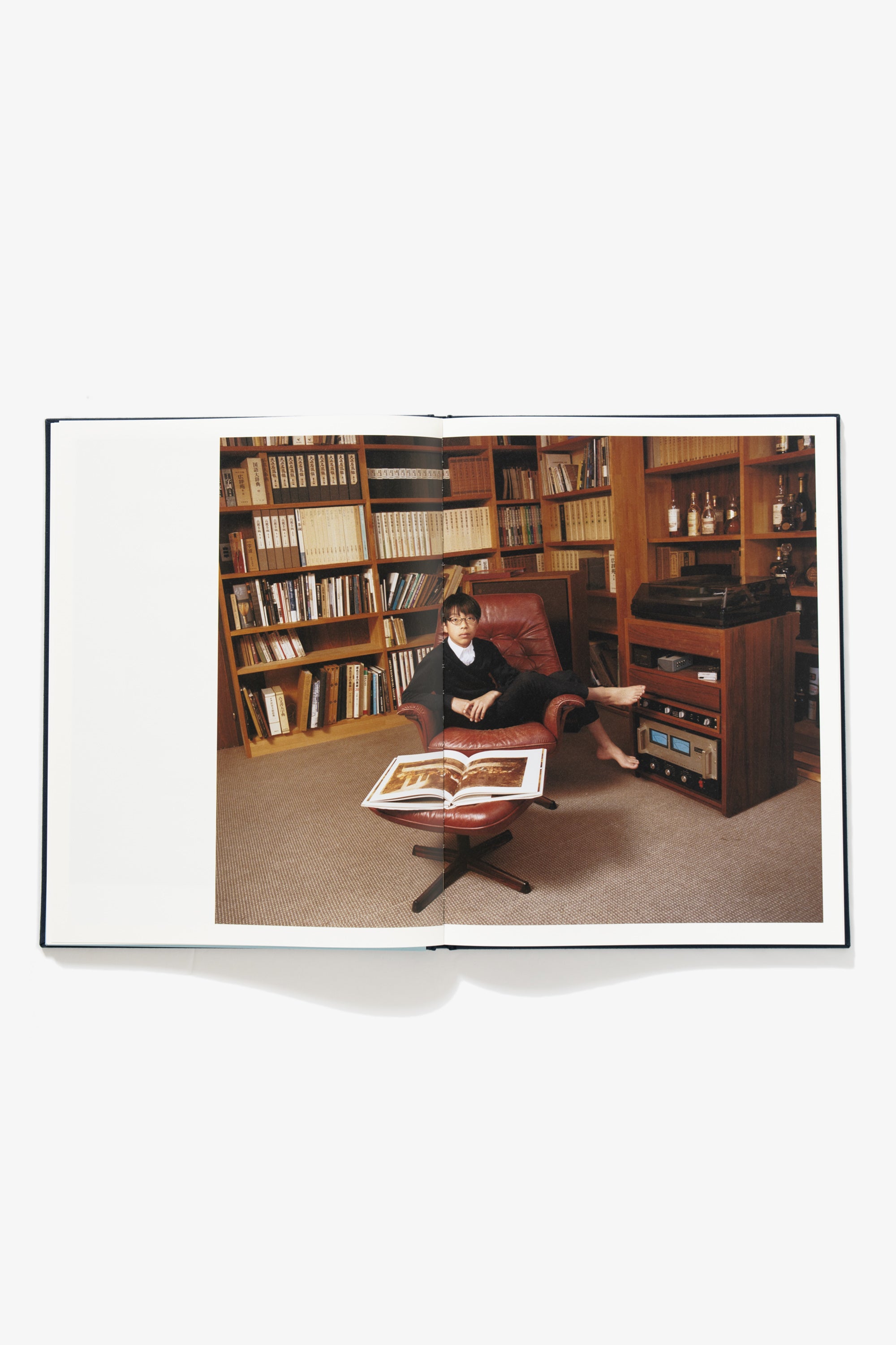 Spread of Goodbye Blue Spring. Image occupies both pages of a school boy sitting askew in a leather lounge chair in a room, with vintage stereo equipment to his right. 