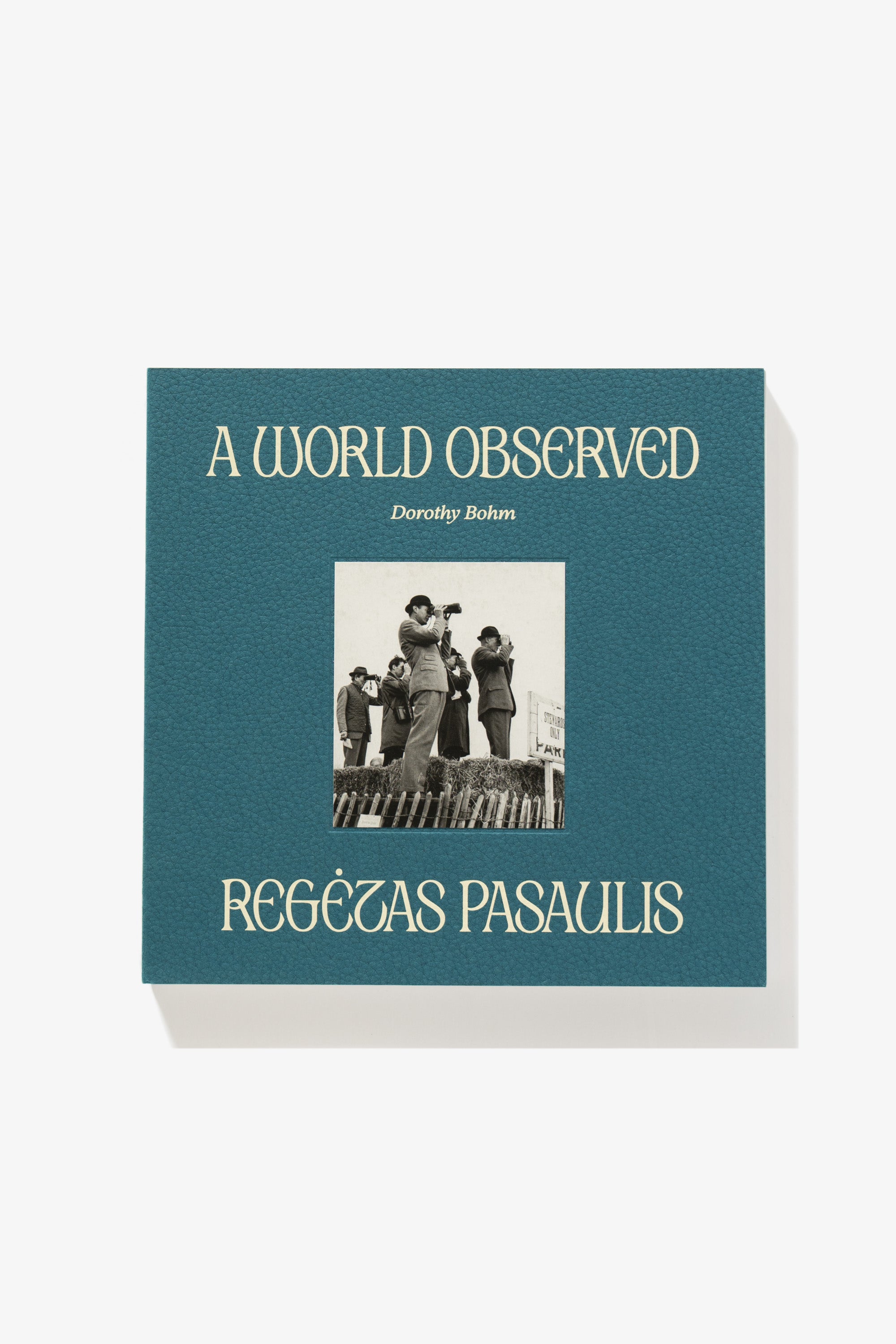 Full-length image of the cover of Dorothy Bohm’s A World Observed. Titles sandwich an image of a suited man peering into the distance through binoculars. The textured surface of the cover material is apparent.