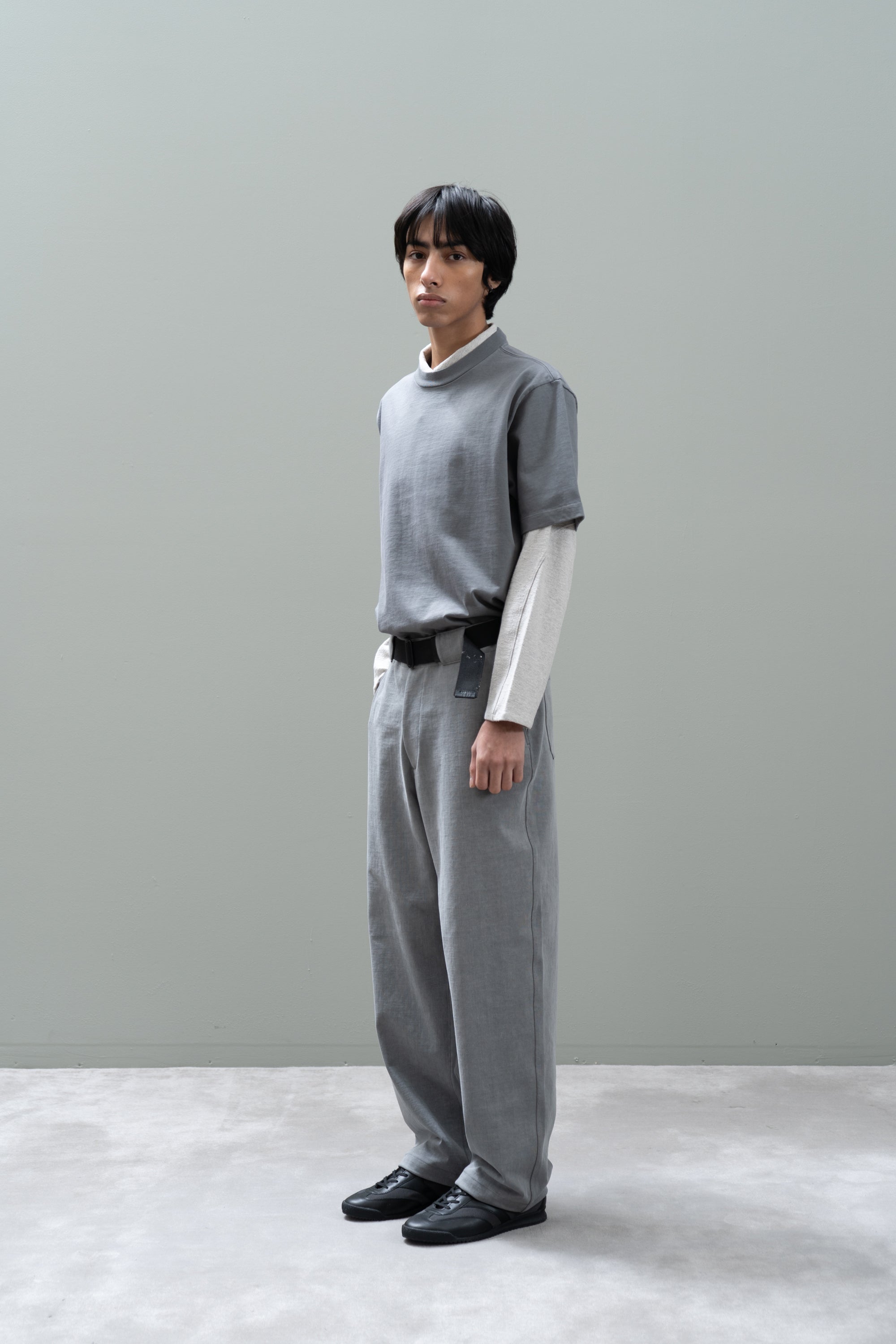 Person wearing a gray turtleneck sweater and pants with a plain background