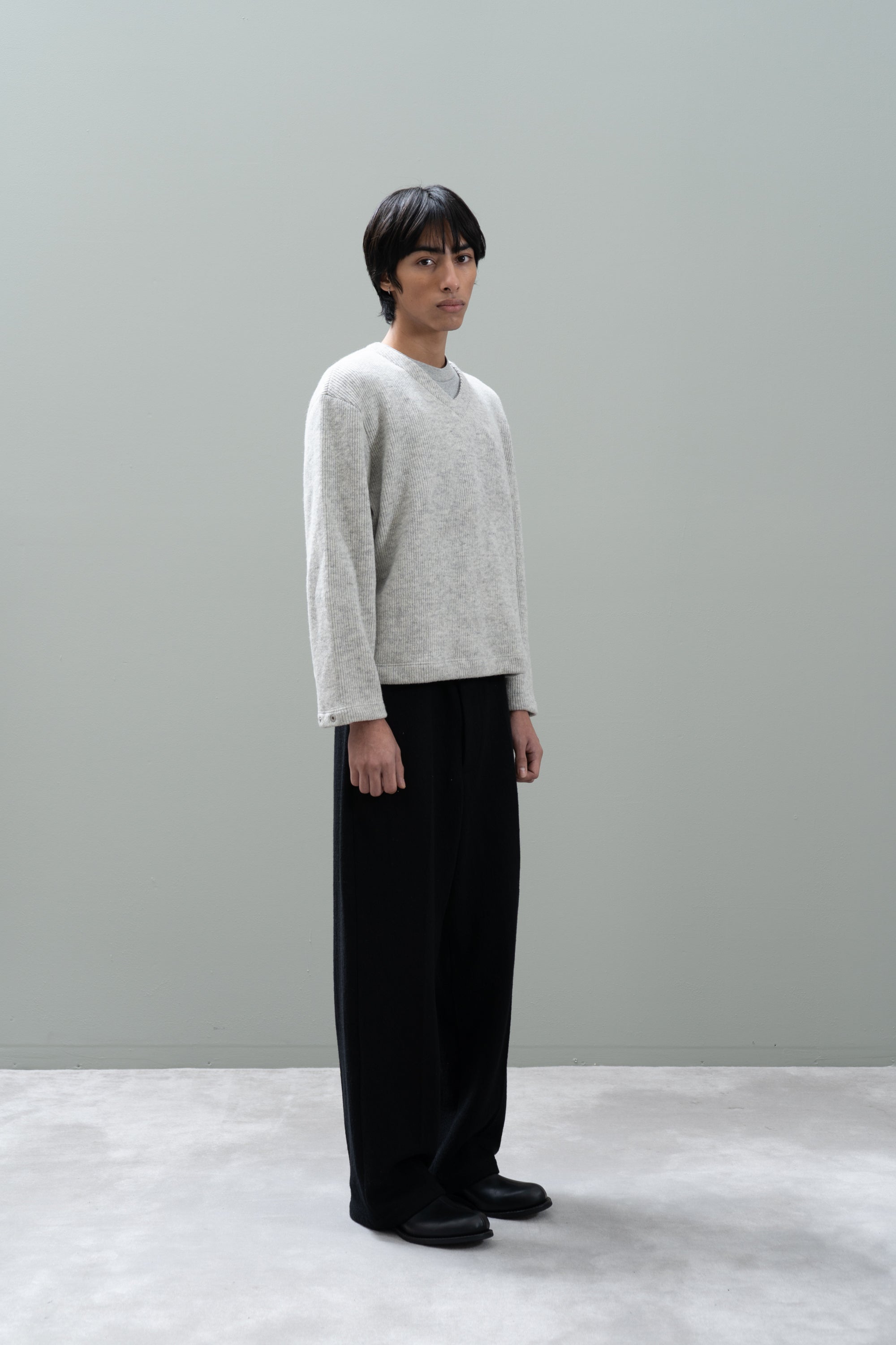 Model poses with a LW770CW V Neck Snap Sweater againsnt a gray background