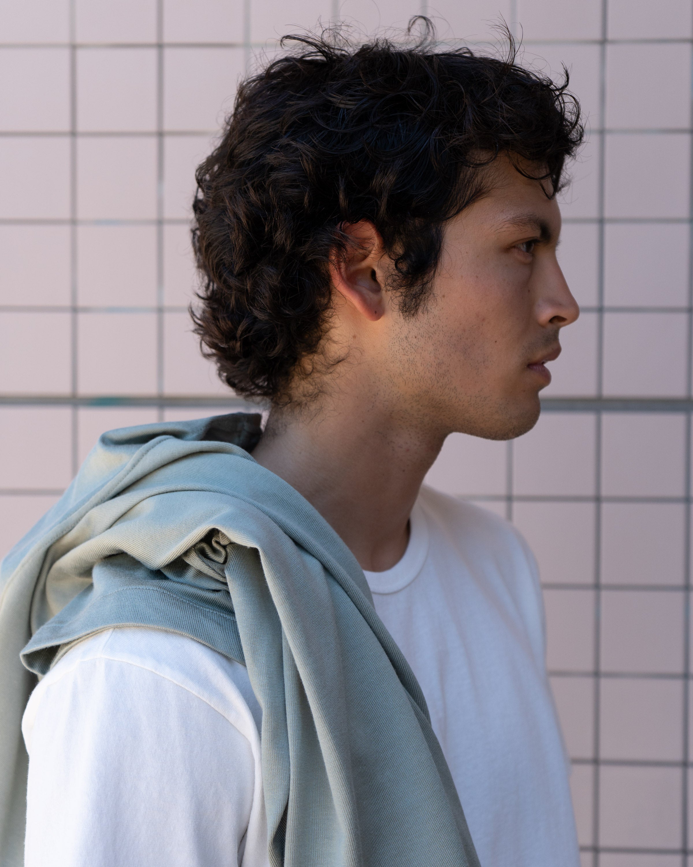 Profile of the model wearing LW101 "Our T-shirt" in white, with LW423CR SS CR Button Down in Pistachio draped over shoulder