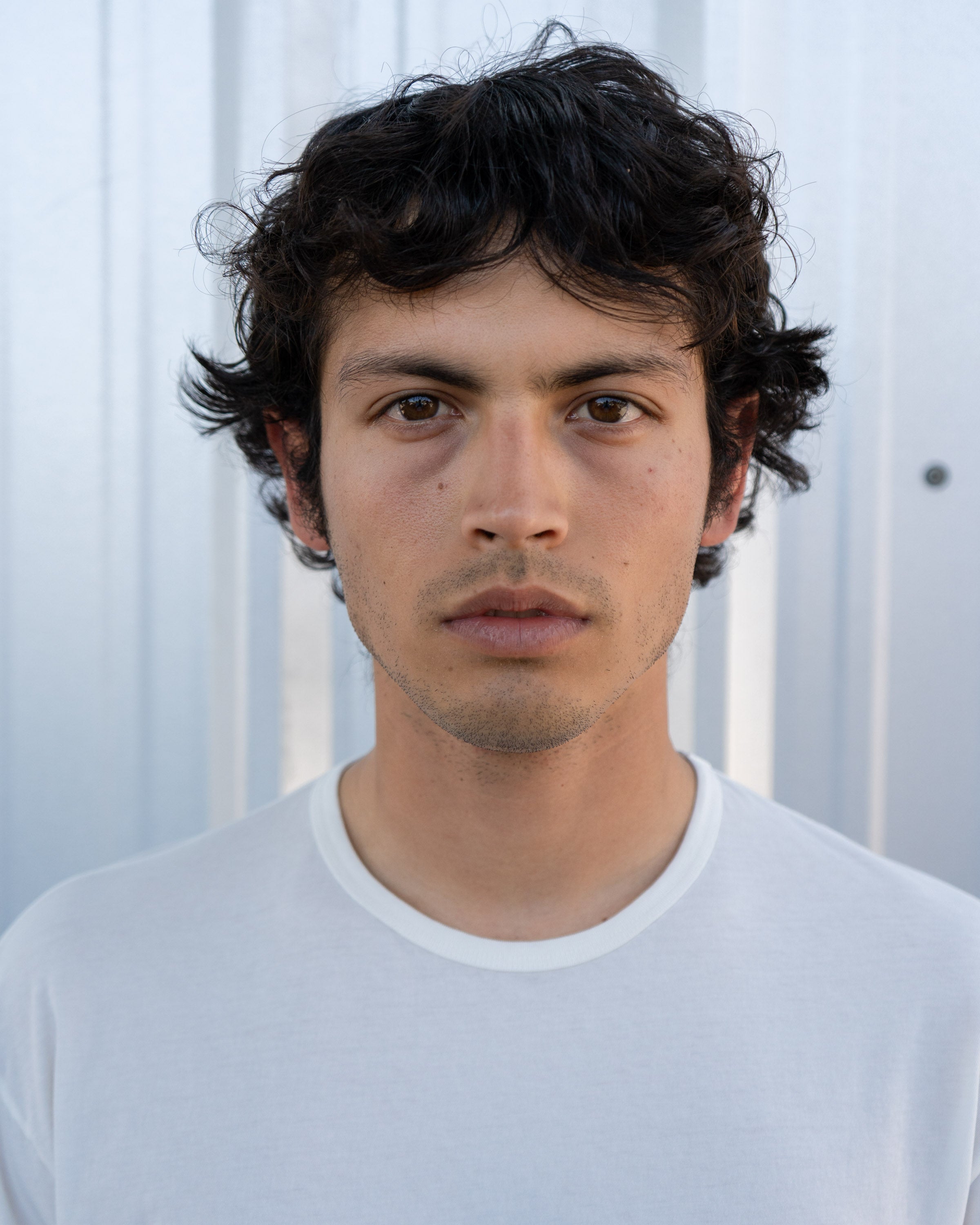 Portrait of model wearing LW110 Dry Lite T-shirt in White against a metal corrugated background
