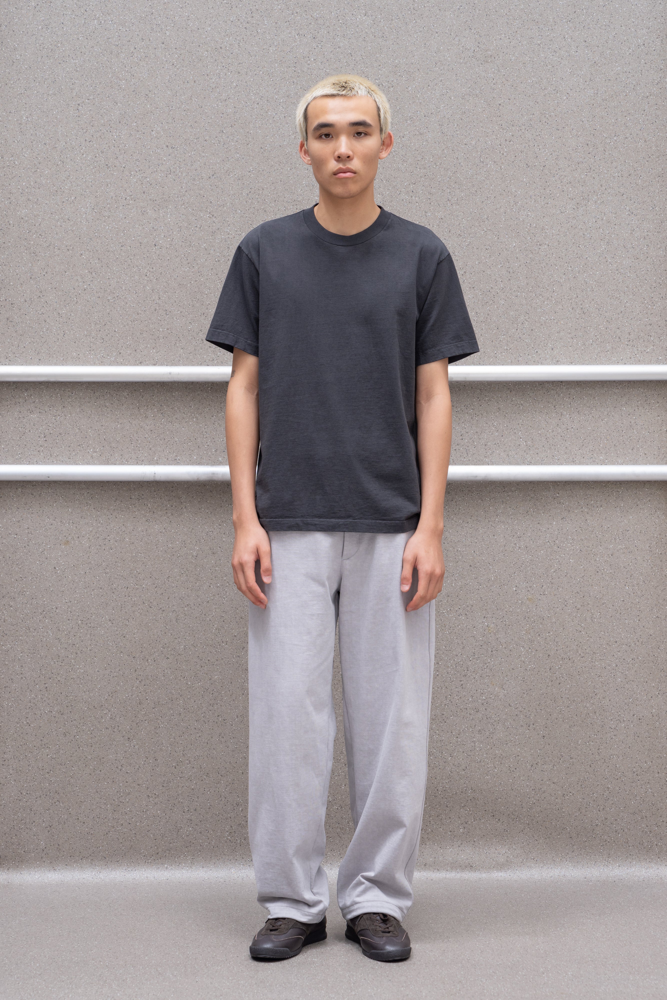 A model wears the LW102 Municipal T-shirt in shadow against a grey background, standing directly in front of the camera