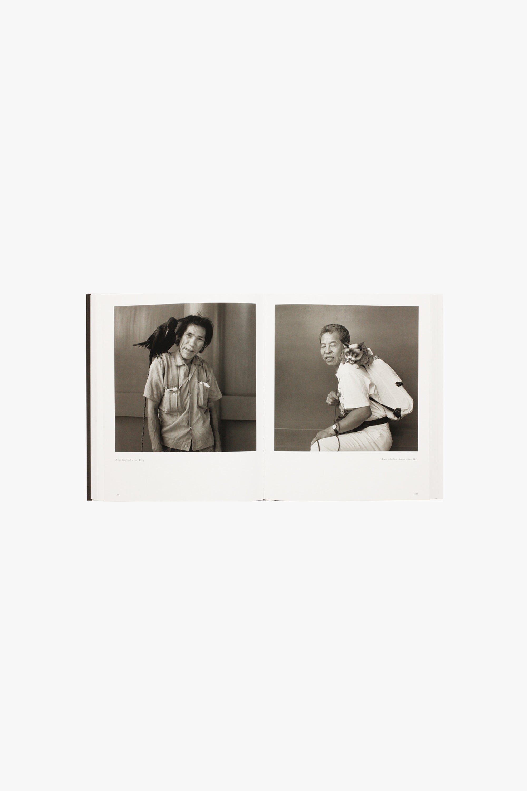 Photograph from Hiroh Kikai's "Asakusa Portraits." Verso shows a middle-aged man posing with a crow on his shoulder. Recto shows a middle-aged man posing with a cat on his back. 