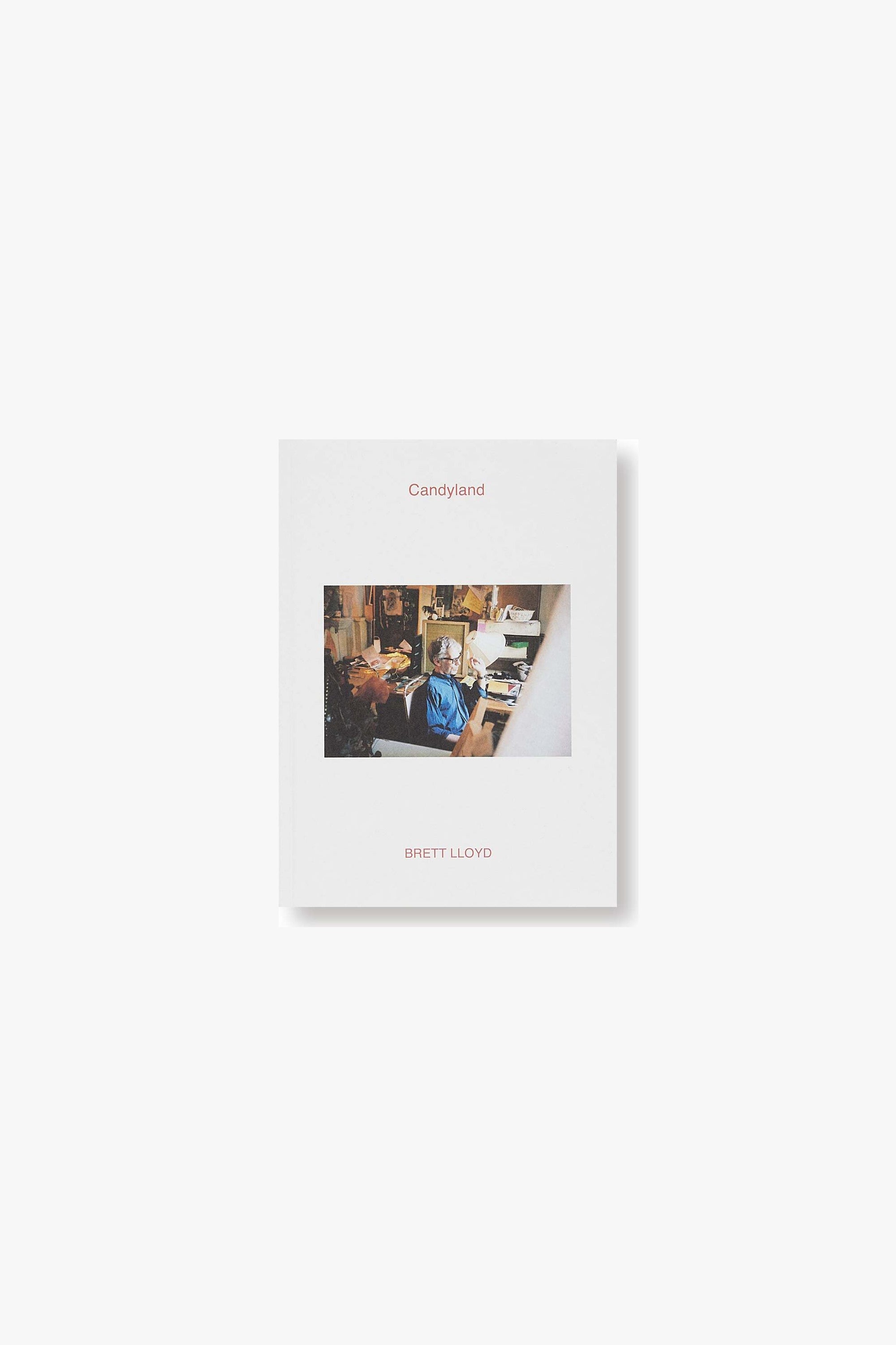 Front cover of "Candyland" by Brett Lloy,d with the photographer seated in his office surrounded by papers and objects.