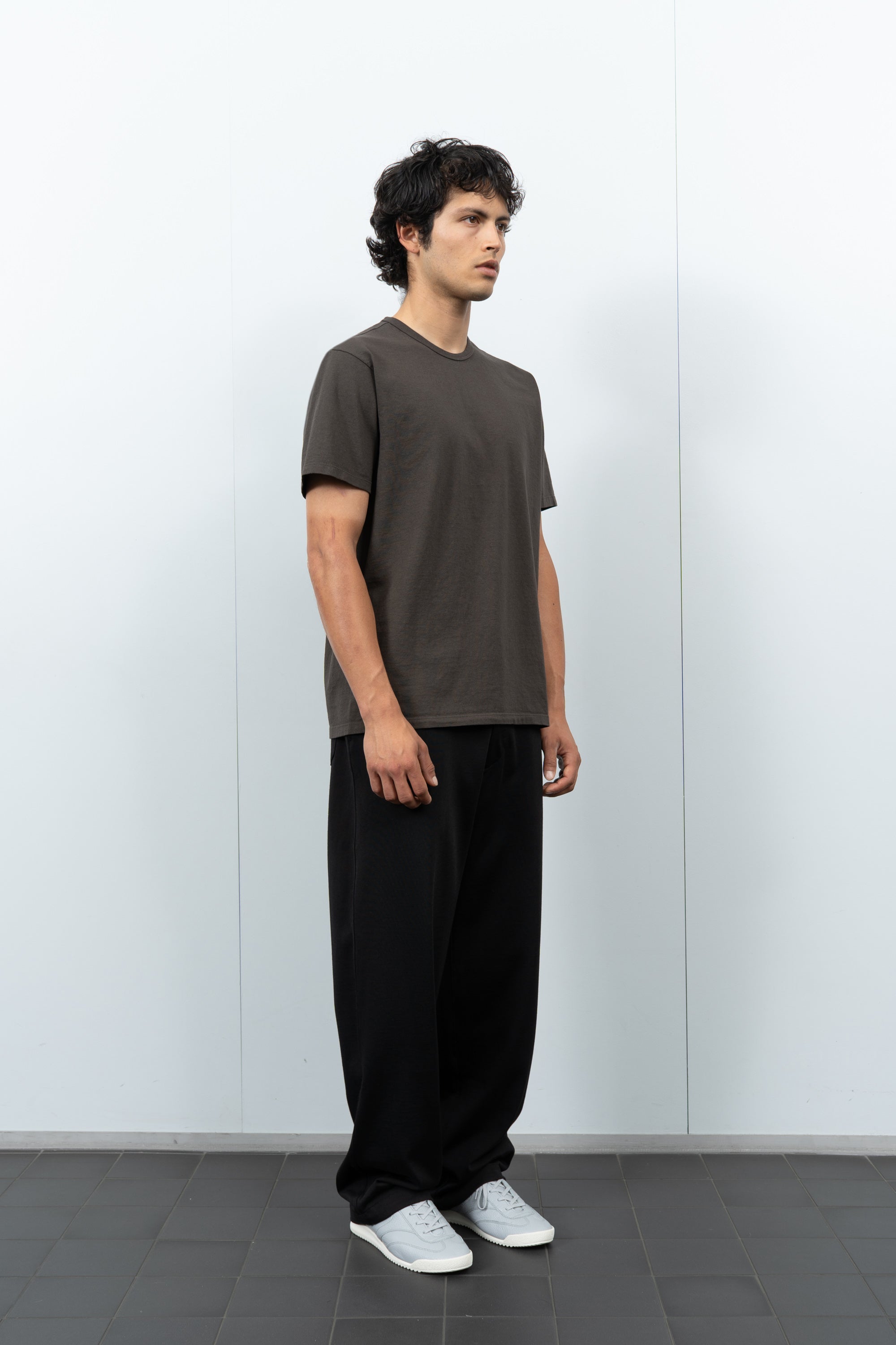 Quarter-turn rear-facing on-model photograph of model wearing LW101 Our T-shirt in Black Pine