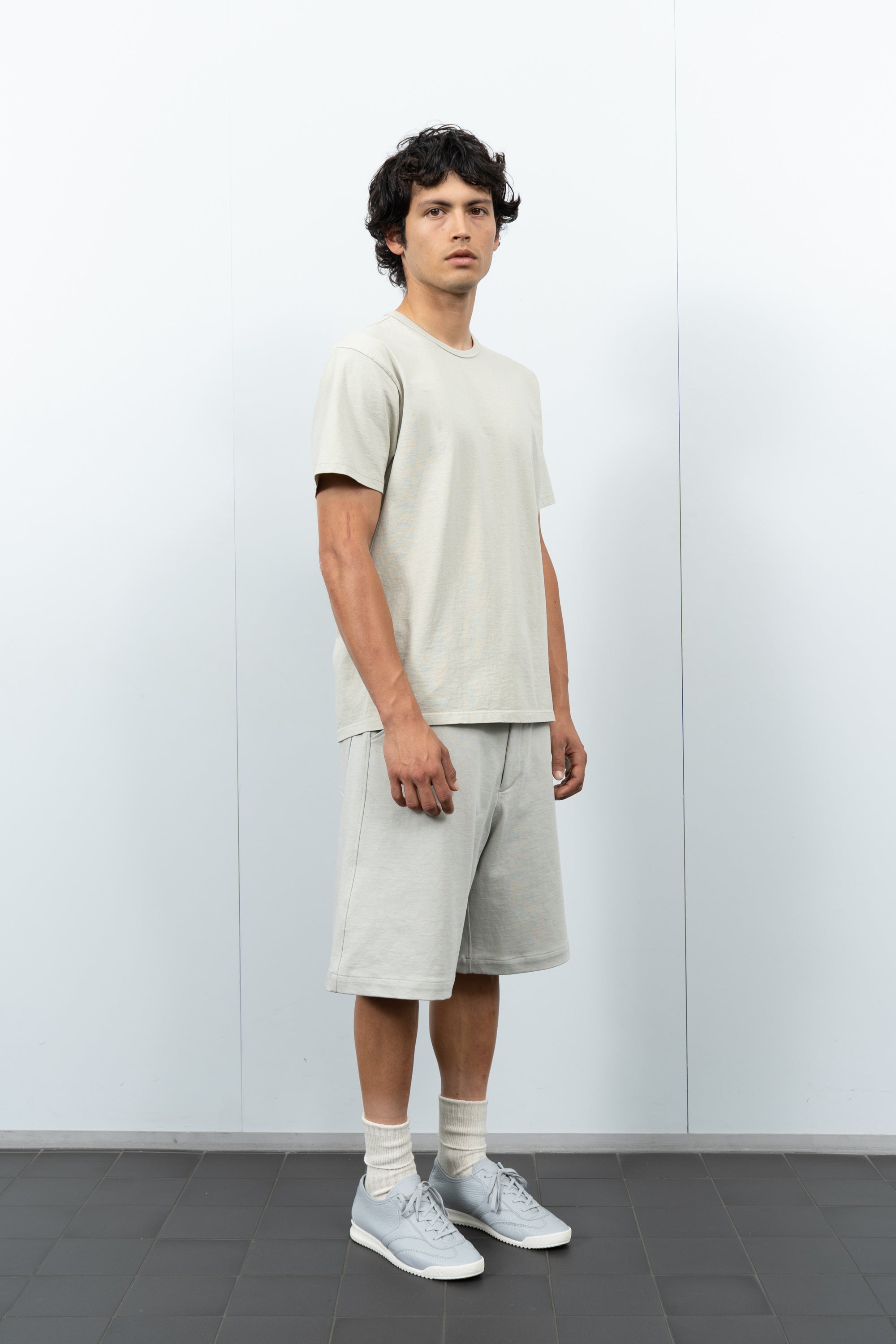 Quarter-turn rear-facing on-model photograph of model wearing LW101 Our T-shirt in Swiss Natural