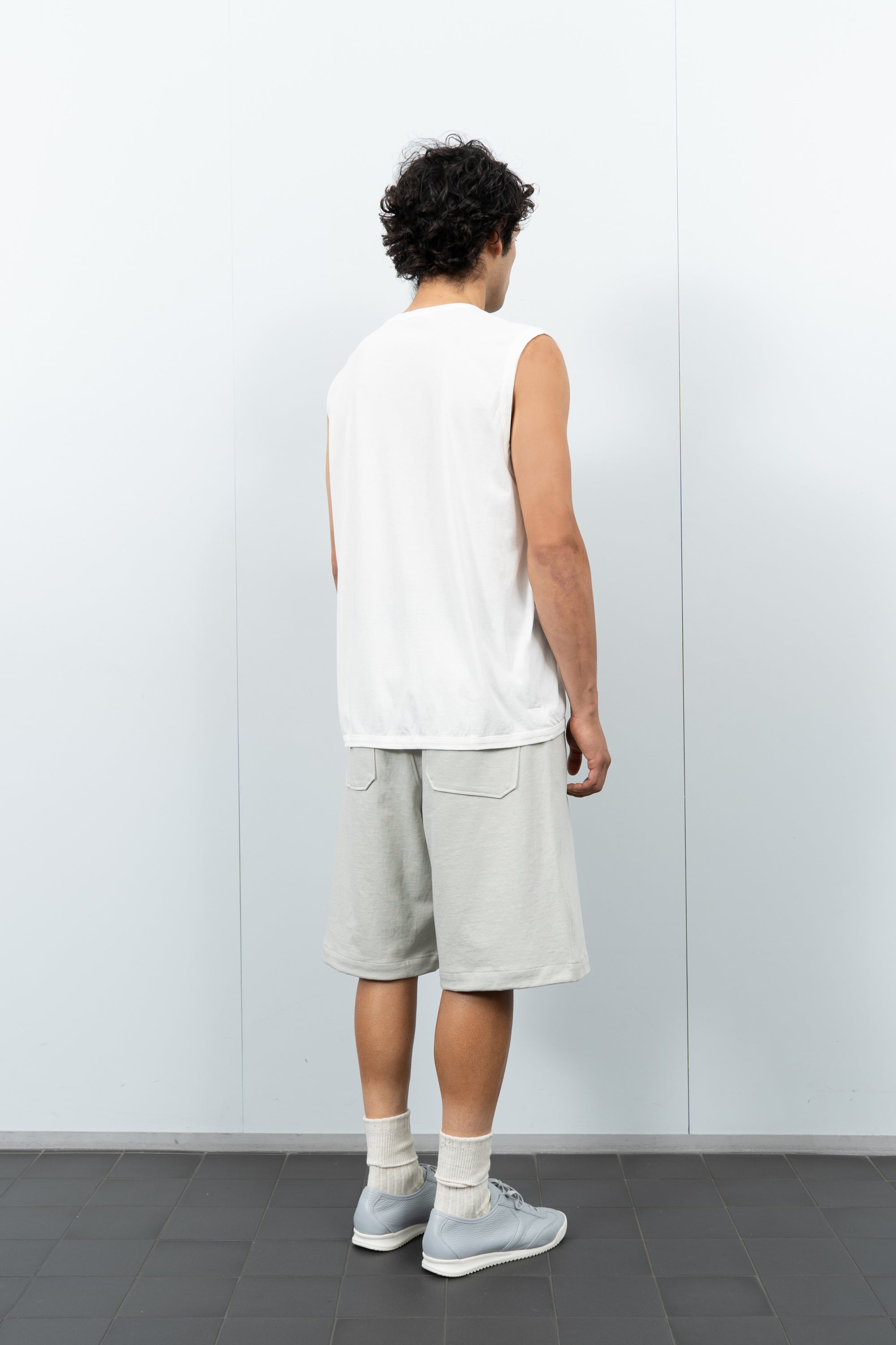 Quarter-turn rear-facing on-model photograph of model wearing LW106 Sleeveless T-shirt in White