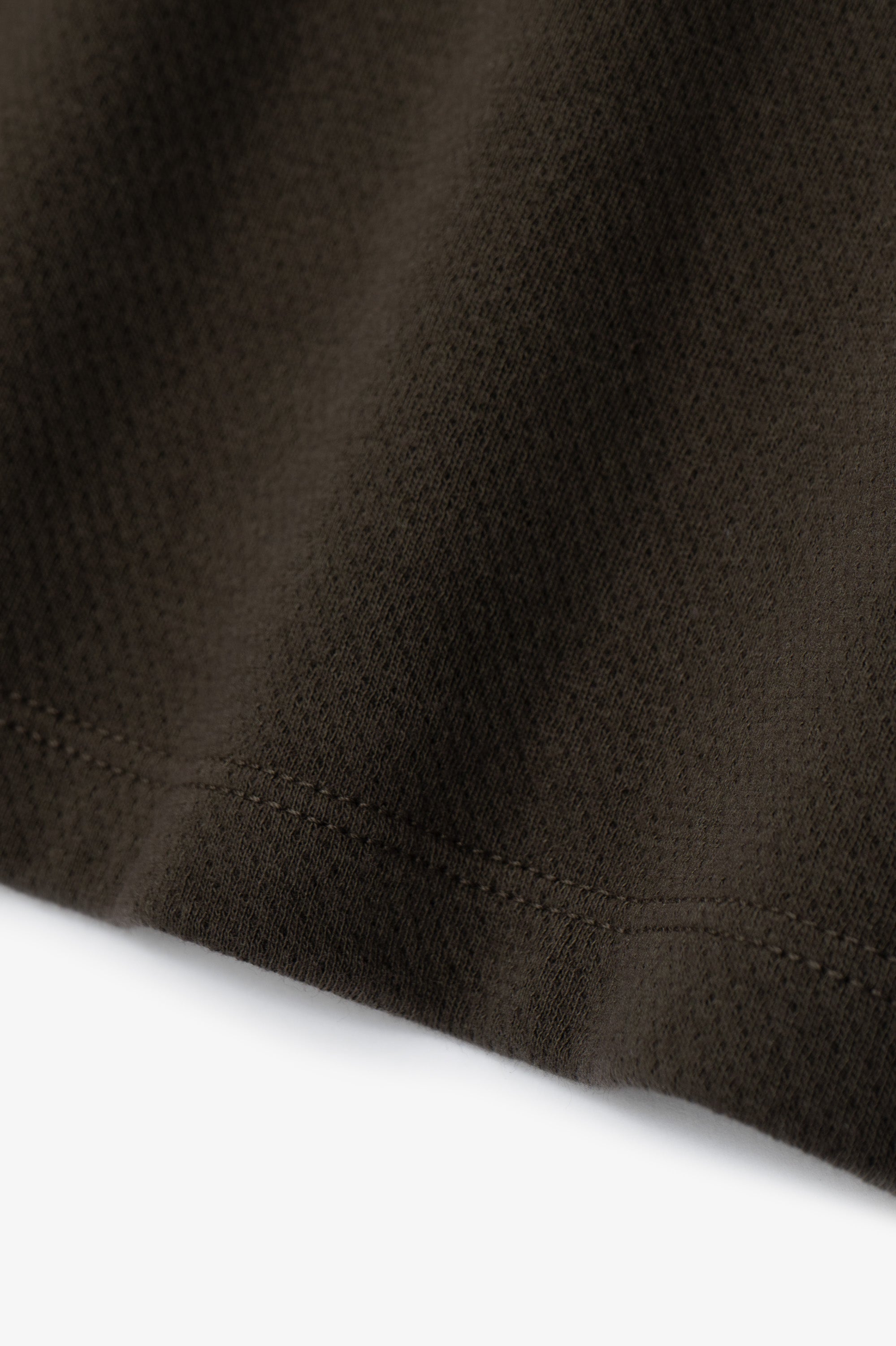Hem detail of of the LW134T Mesh T-shirt in a greenish black, “Black Pine”