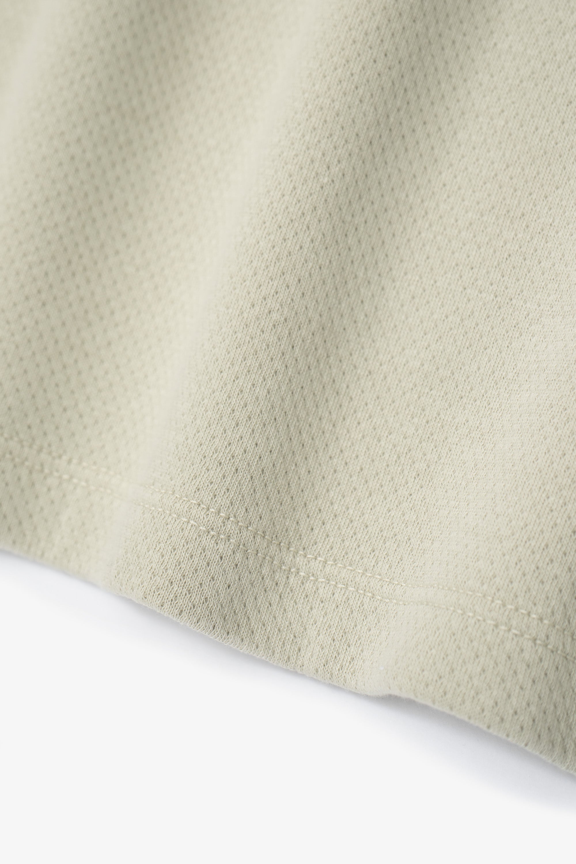 Hem detail of the LW134T Mesh T-shirt in a creamy green, “Swiss Natural”