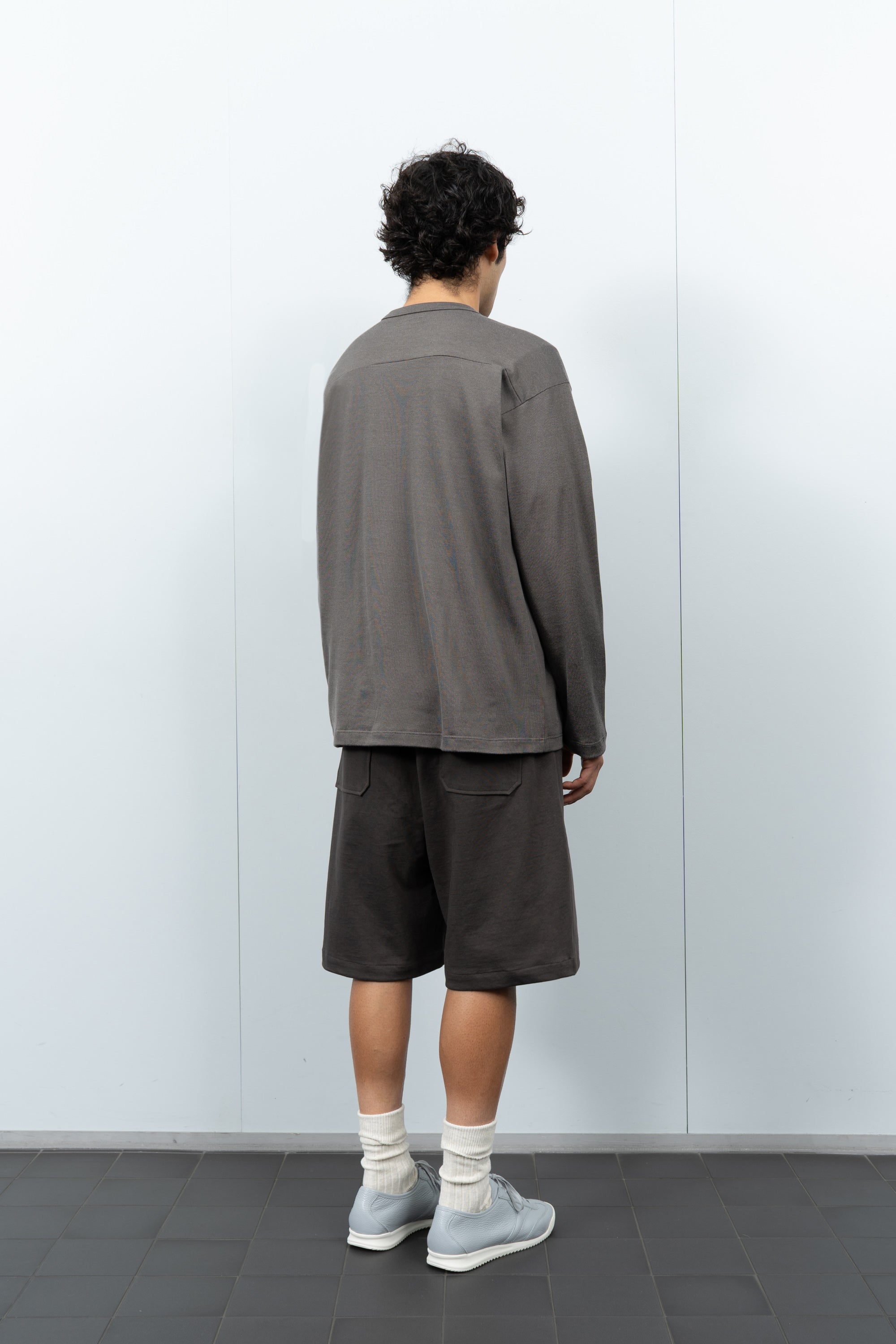 Quarter-turn rear-facing on-model photograph of model wearing LW135 LS Football T-shirt in Grey Olive