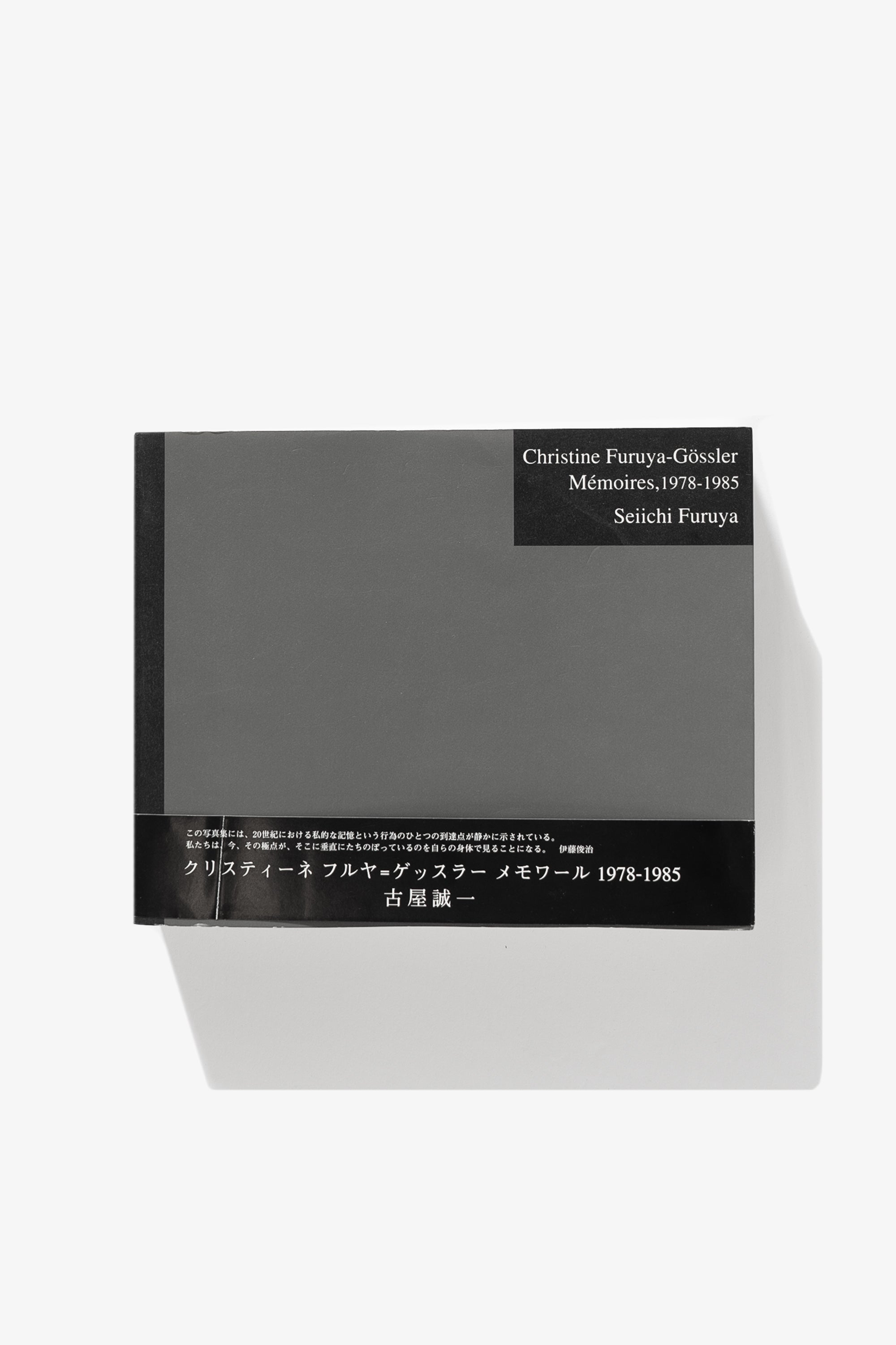 Cover of Seiichi Furuya's book of photography, "Christine Furuya-Gössler Mémoires, 1978-1985," a textured grey panel with black accents in the corner and binding. 