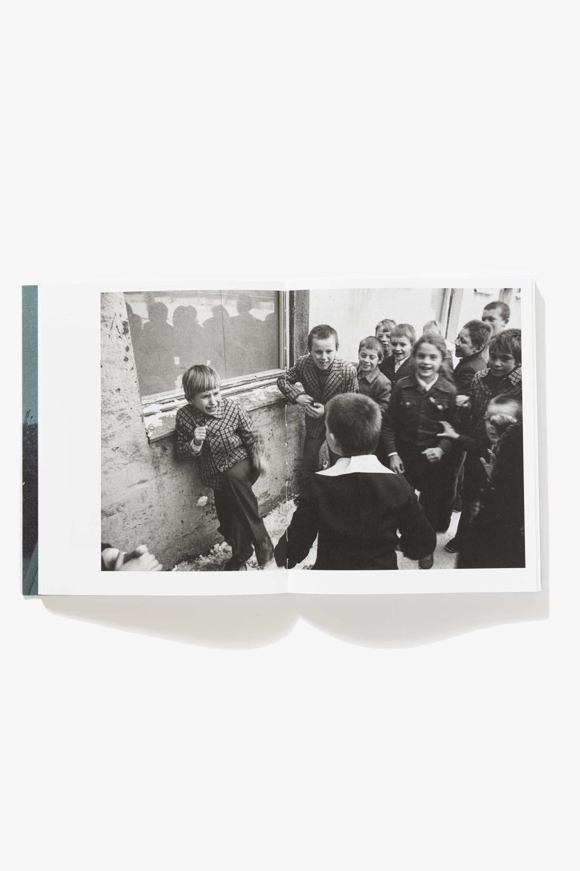 Spread of School is my Home. Image occupies both pages, of a boy confronting a classmate, his knee lifted in a defensive position. Other school-aged children surround the two.